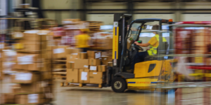 yellow forklift blurred in warehouse to emphasize it's moving quickly and using advanced telematics systems